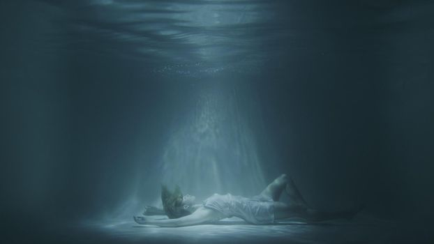 a girl in a white dress falls under the water in 4k