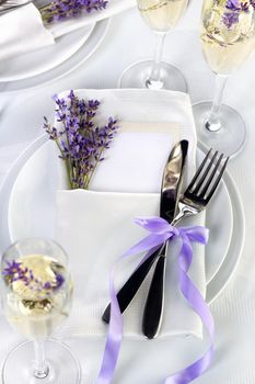 Dining table in Provence style, with Lavender Champagne, folded napkin with cutlery, decorated with fresh lavender. Detail of the wedding dinner. Wedding theme ideas.