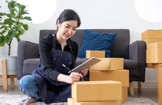 Portrait of Asian young woman SME working with a box at home the workplace.start-up small business owner, small business entrepreneur SME or freelance business online and delivery concept..