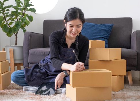 Portrait of Asian young woman SME working with a box at home the workplace.start-up small business owner, small business entrepreneur SME or freelance business online and delivery concept..