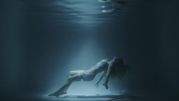 girl in a white dress swims underwater in 4k