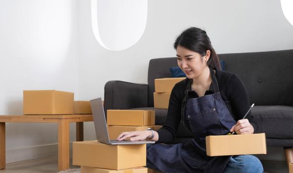 Portrait of Asian young woman SME working with a box at home the workplace.start-up small business owner, small business entrepreneur SME or freelance business online and delivery concept..