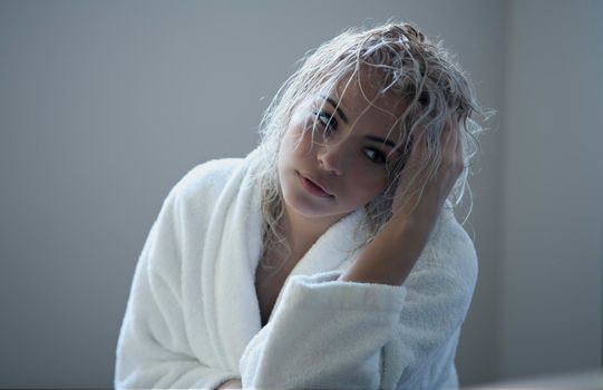 Portrait of a beautiful attractive sexy and sensuality young adult pretty blonde woman after bath relaxing in a bathrobe