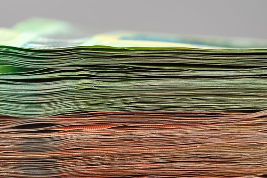 Close-up of a stack of paper bills, side view. Euro banknotes stacked on top of each other. Big pile of money