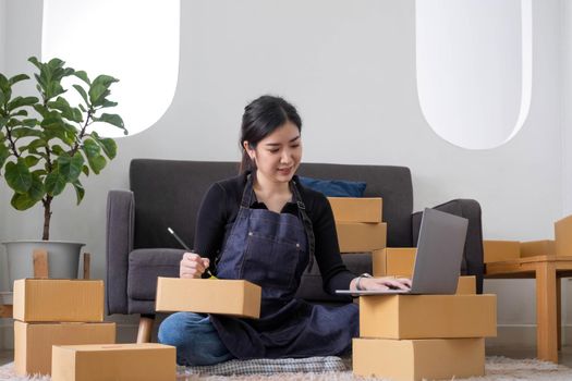 Portrait of Asian young woman SME working with a box at home the workplace.start-up small business owner, small business entrepreneur SME or freelance business online and delivery concept..