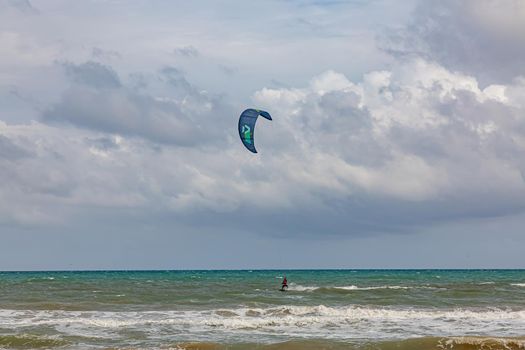 Professional kiter makes the difficult trick on a beautiful background. Kitesurfing Kiteboarding action photos man among waves quickly goes.