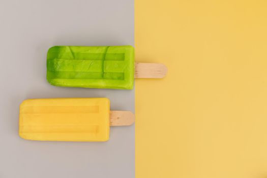Ice cream stick on gray and yellow background.