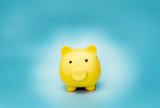 Yellow piggy bank on blue background