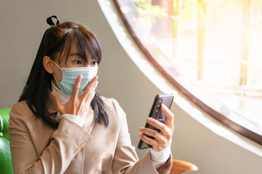 Business woman wearing surgical mask and using smartphone for work, social media