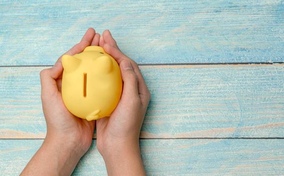 Hand hold piggy bank for save money on wooden background