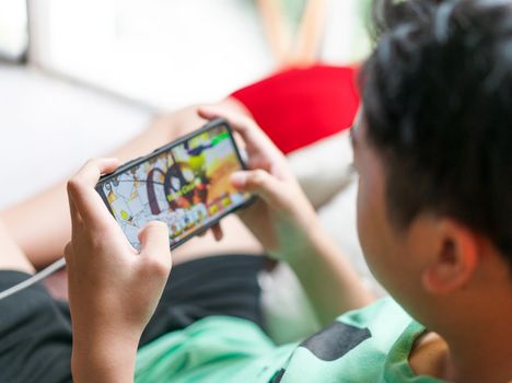 Hand kid holding smartphone for playing game online at home