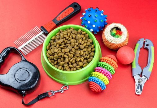 Pet food in bowls, toy, for pets on red background