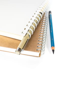 White and brown spiral notebook with pencil and pen
