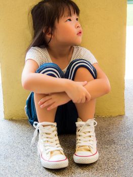 A Lonely girl sitting behind the concrete wall