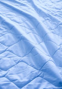 Blue blanket crumpled on the bed