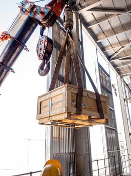 The crane carrying a wooden box of the radioactivity holder into the window on the factory floor