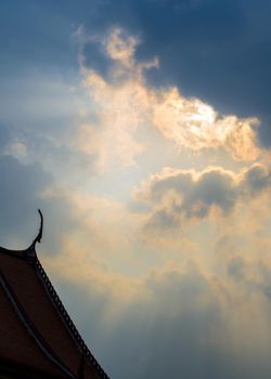 Sun beam behind the sunset clouds over the buddhist temple