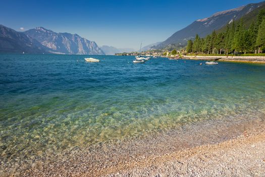 Idyllic lake Garda coastline in Malcesine with sailboats and mountains, Northern Italy