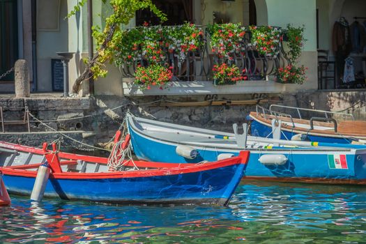Idyllic Limone sul Garda pier with colorful boats at summer, Lake Garda, Italian alps
