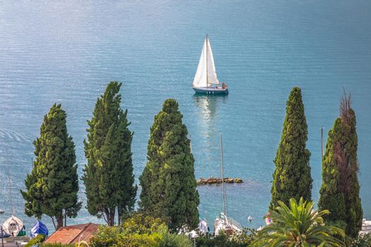 Above idyllic Lake Garda in Malcesine with sailboat at sunset, northern Italian alps