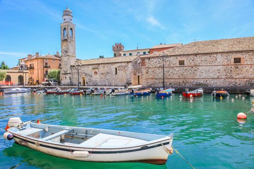 Idyllic lake Garda coastline in Lazise with boat and mountains, Northern Italy