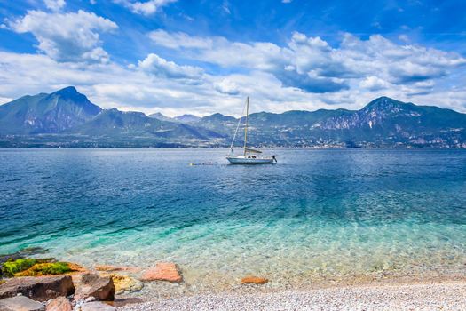 Idyllic lake Garda coastline in Malcesine with sailboats and mountains, Northern Italy