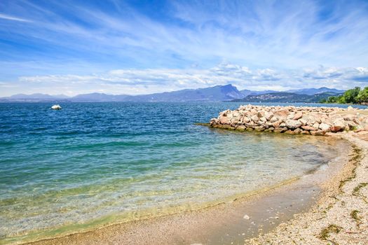 Idyllic lake Garda coastline in Lazise with boat and mountains, Northern Italy