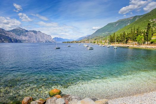Idyllic lake Garda coastline in Malcesine with sailboats and mountains, Northern Italy