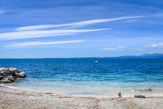 Idyllic lake Garda coastline in Lazise with boat and mountains, Northern Italy