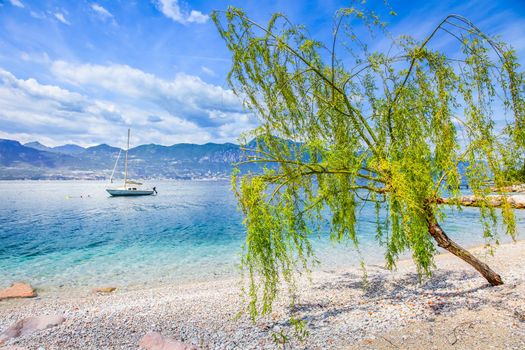 Idyllic lake Garda coastline in Malcesine with sailboats and mountains, Northern Italy