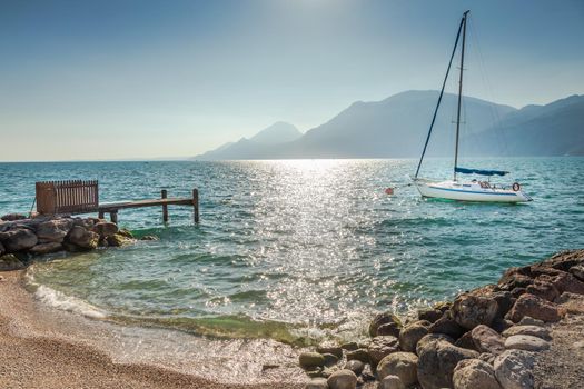 Idyllic lake Garda coastline in Malcesine with sailboats and mountains, Northern Italy