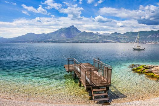 Idyllic lake Garda coastline in Malcesine with sailboats and mountains, Northern Italy