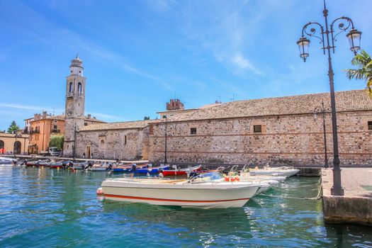 Idyllic lake Garda coastline in Lazise with boat and mountains, Northern Italy