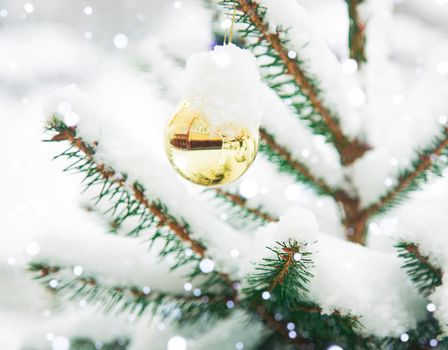 Christmas tree with snow on the branches. The traditional decoration is a gold ball on the Christmas tree. Christmas Tree Toy
