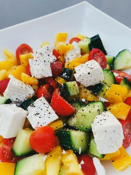 Fresh vegetable greek salad with cherry tomatoes, bell pepper, cucumber, feta cheese, olive oil and seasonal spices, healthy food diet and delicious meal recipe concept