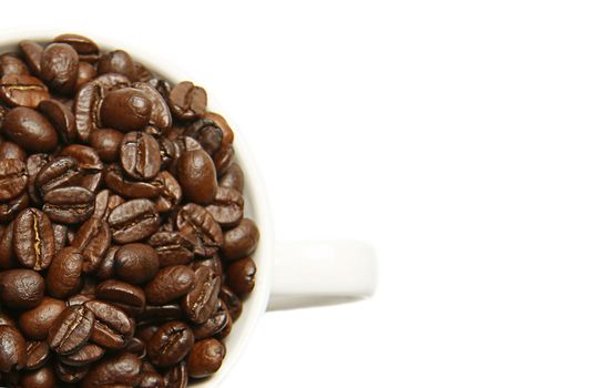 Roasted coffee beans in a white mug on a white background. Isolate. Top view. Close-up. Macro shooting.