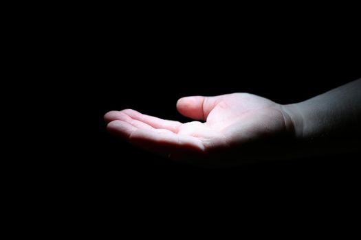 A man's hand on a black background. Isolate. The palm of a person in the dark is illuminated by white light.