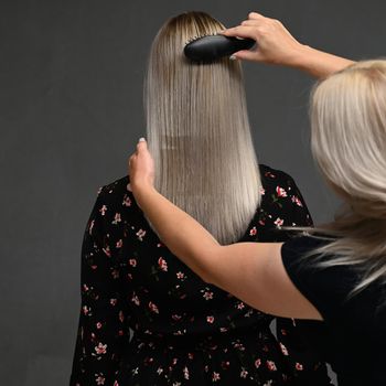 Hairdresser's hands combing model's hair from behind