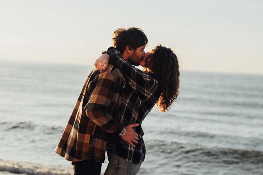 Woman and man hugging and kissing with sea on background, young couple fall in love