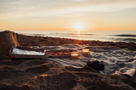 Picnic set with pizza on the beach at dawn, concept of meeting sunrise on sea