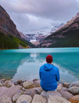 Lake Louise Canadian Rockies Banff national park, Beautiful autumn views of iconic Lake Louise in Banff National Park in the Rocky Mountains of Alberta Canada. young men sitting on a rock by the lake