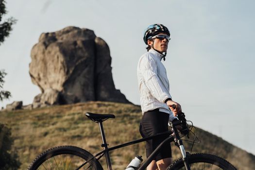 Portrait of Professional Equipped Cyclist on Trail with Giant Stone on Background, Adult Man Riding Bike Outdoors