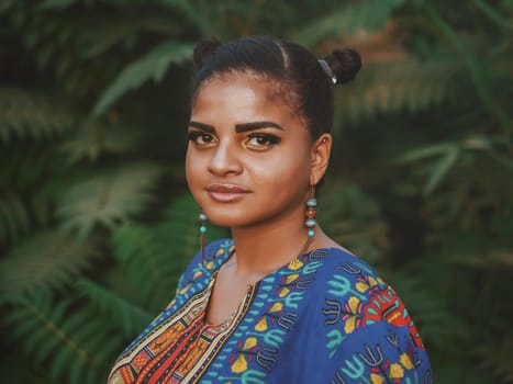 Afro-american woman outdoor. Multi ethnic girl wearing colorful clothing posing, enjoys the nature. Green tropical background