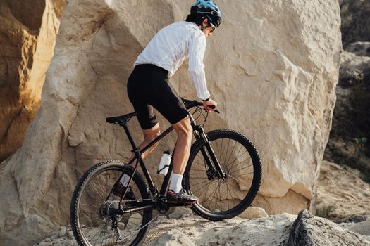 Adult Man Riding Bike Outdoors, Professional Equipped Cyclist on Trail with Giant Sandy Stones