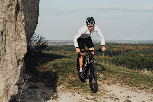 Equipped Professional Male Cyclist Riding Bike Outdoors on Top of Hill