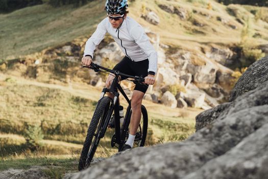 Close Up Professional Male Cyclist Riding Mountain Bike on Trail Among Rocky Terrain