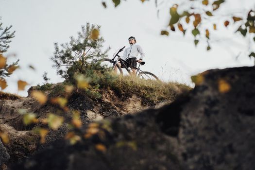 Professional Cyclist Standing with His Bike on Top of the Edge of Rock Mountain