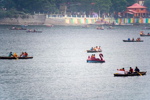 Nanital, Uttarakhand, India - circa 2022 : foggy lake at bhimtal filled with row boats piloted by locals carrying tourists come to visit this famous hill station in the monsoons for the natural beauty