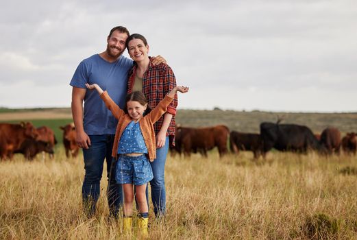 Happy family standing on a farm, cow in background and with a vision for growth in industry portrait. Countryside couple, people or farmer in a field of grass, cattle and free range livestock animals.