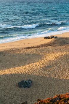 The coast of the Atlantic Ocean with a sandy beach in the rays of the setting sun view